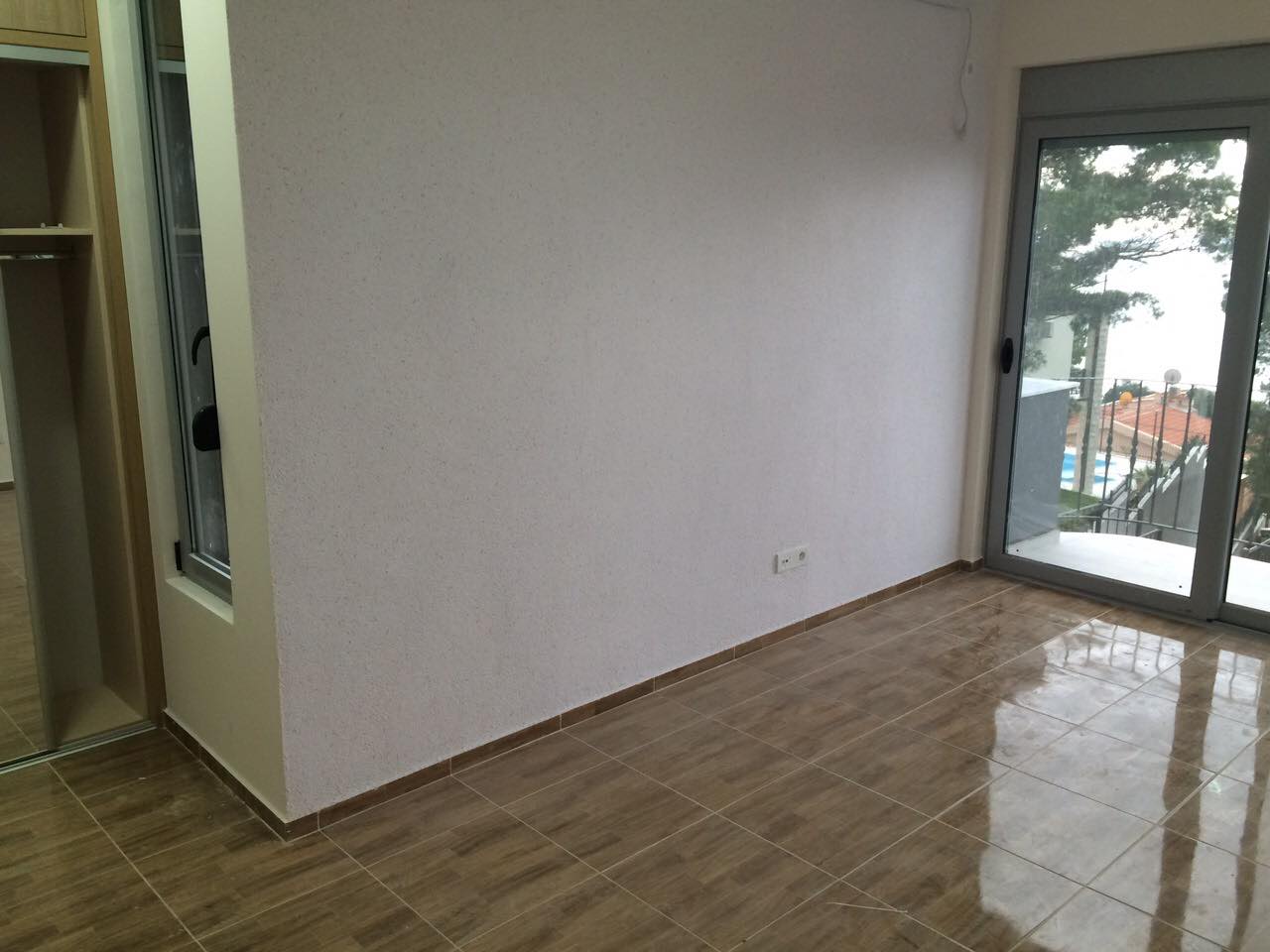 Helles Wohnzimmer in einem Haus in Šušanj, Montenegro: Fliesenboden, Einbauschrank und Zugang zum Balkon mit Meerblick.