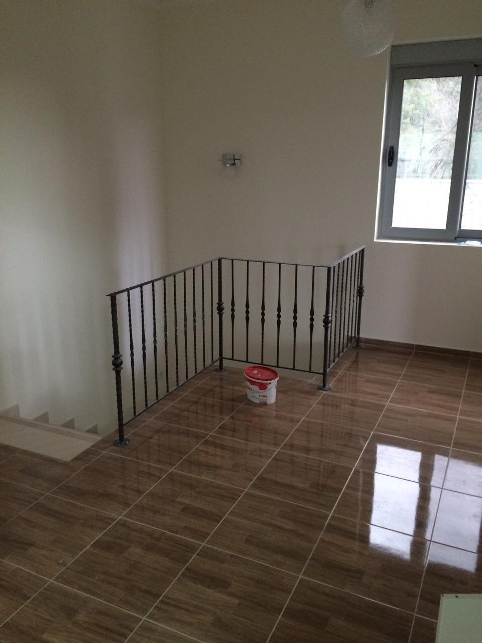 Wohnzimmer mit Treppe und schmiedeeisernem Geländer im Haus, Šušanj, Montenegro. Helle Ausstattung und Fliesenboden in Holzoptik.