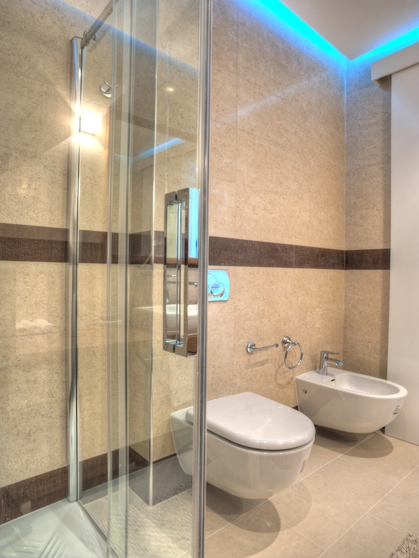 Modernes Badezimmer in einer Wohnung in Budva, Montenegro: Duschkabine, wandhängendes WC, Bidet und LED-Beleuchtung.