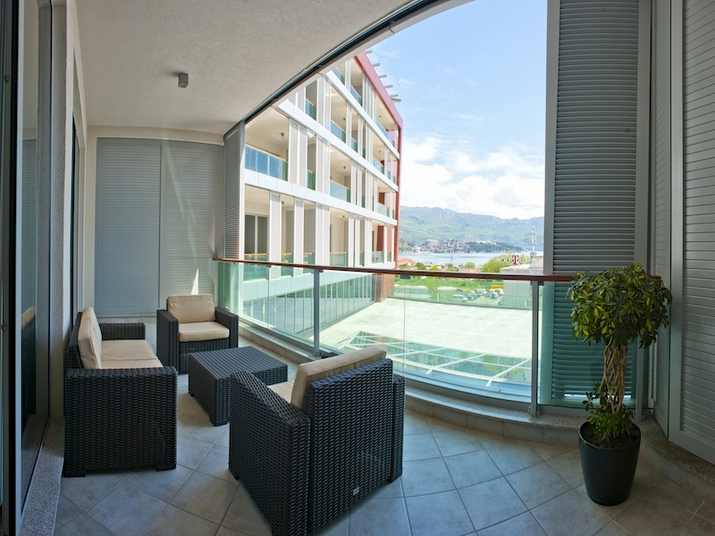Terrasse mit Rattanmöbeln in einer Wohnung in Budva, Montenegro, mit Panoramablick auf das Meer und die Berge.