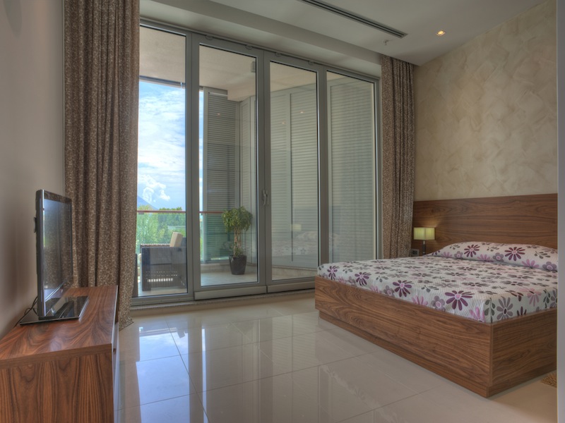 Modernes Schlafzimmer mit Panoramafenstern und Zugang zur Terrasse in einer Wohnung, Budva, Montenegro.