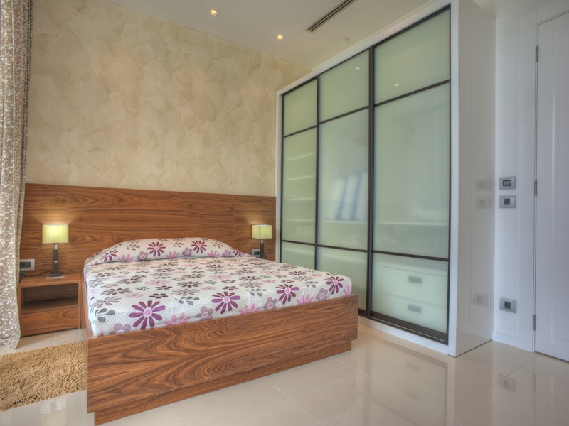 Modernes Schlafzimmer in einer Wohnung in Budva, Montenegro: Doppelbett mit Holz-Kopfteil und Einbauschrank.