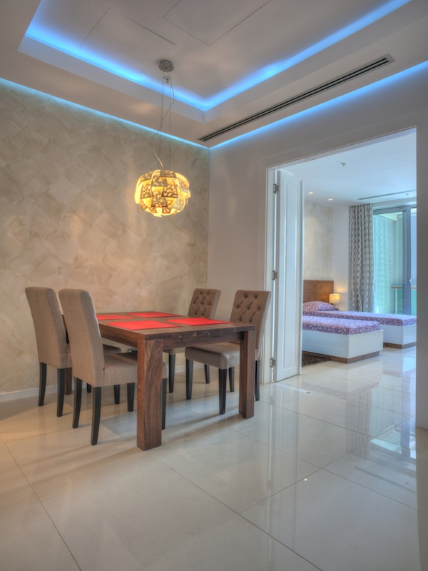 Modernes Wohnzimmer mit Essbereich in einer Wohnung in Budva, Montenegro: Holztisch, weiche Stühle und LED-Beleuchtung.