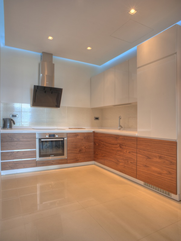 Moderne Küche in einer Wohnung in Budva, Montenegro: glänzende Fronten, Einbaugeräte und Deckenbeleuchtung.