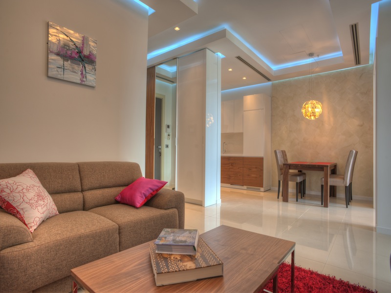 Modernes Wohnzimmer mit Küche in einer Wohnung in Budva, Montenegro: weiches Sofa, Essbereich und stilvolle Beleuchtung.