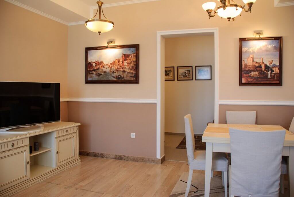 Salon confortable avec coin repas dans l’appartement, Kostanica, Monténégro : mobilier clair, tableaux et décor classique.