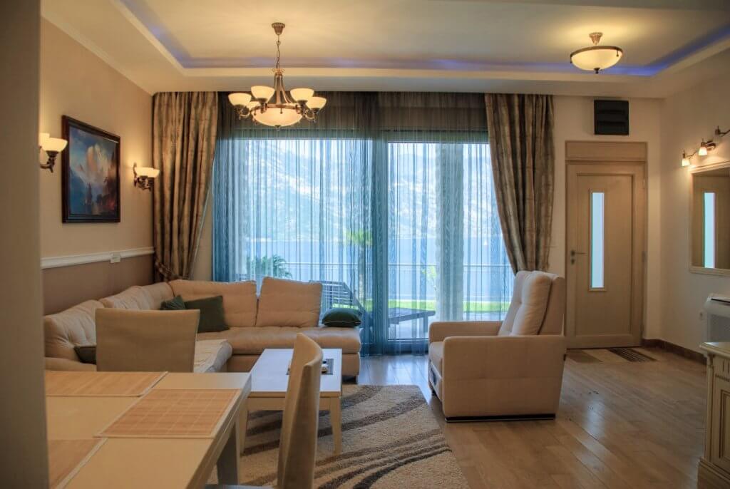 Salon confortable avec mobilier moelleux et vue sur la mer dans un appartement à Kostanica, Monténégro. Intérieur moderne avec terrasse.
