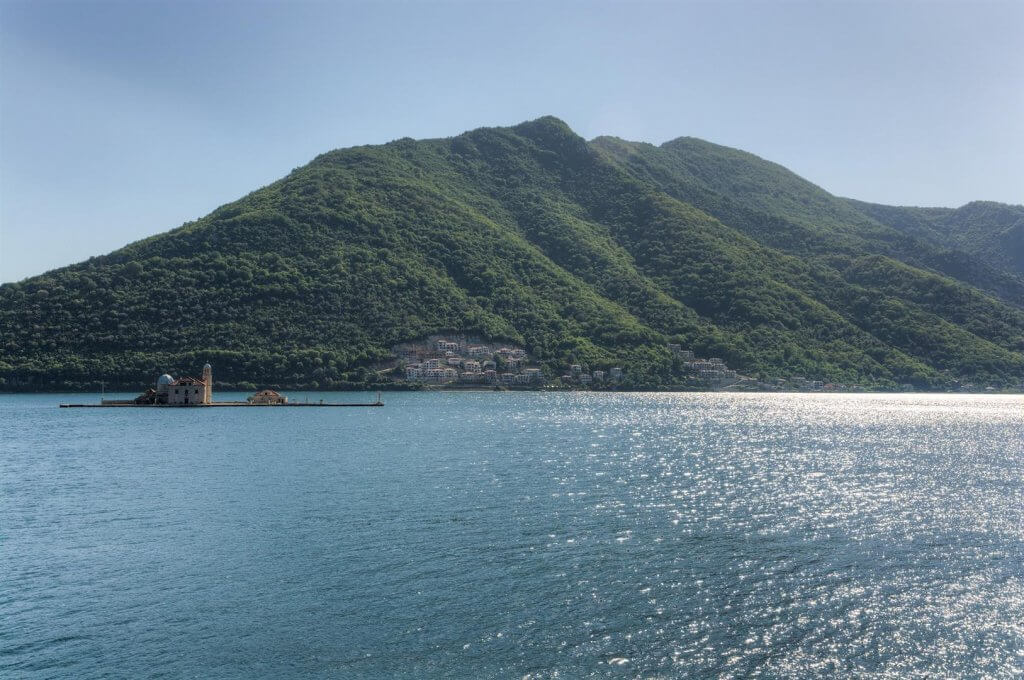 Vue panoramique sur la baie de Kotor et l’île de Gospa od Škrpjela à Kostanjica, Monténégro, avec vue sur les montagnes verdoyantes.