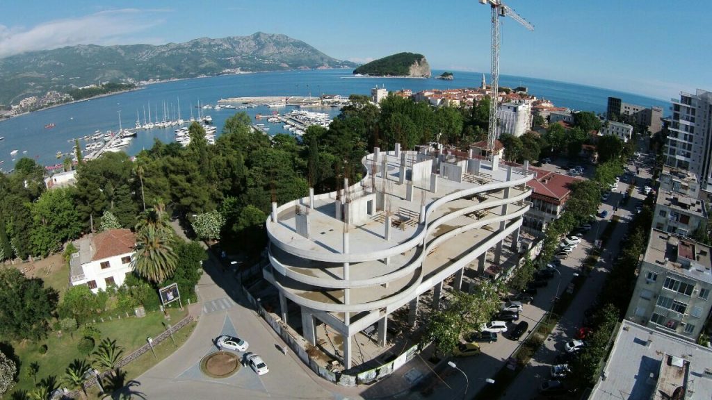 Im Bau befindliche Wohnanlage in Budva, Montenegro: Luftaufnahme eines Massivgebäudes am Meer und des Yachthafens.