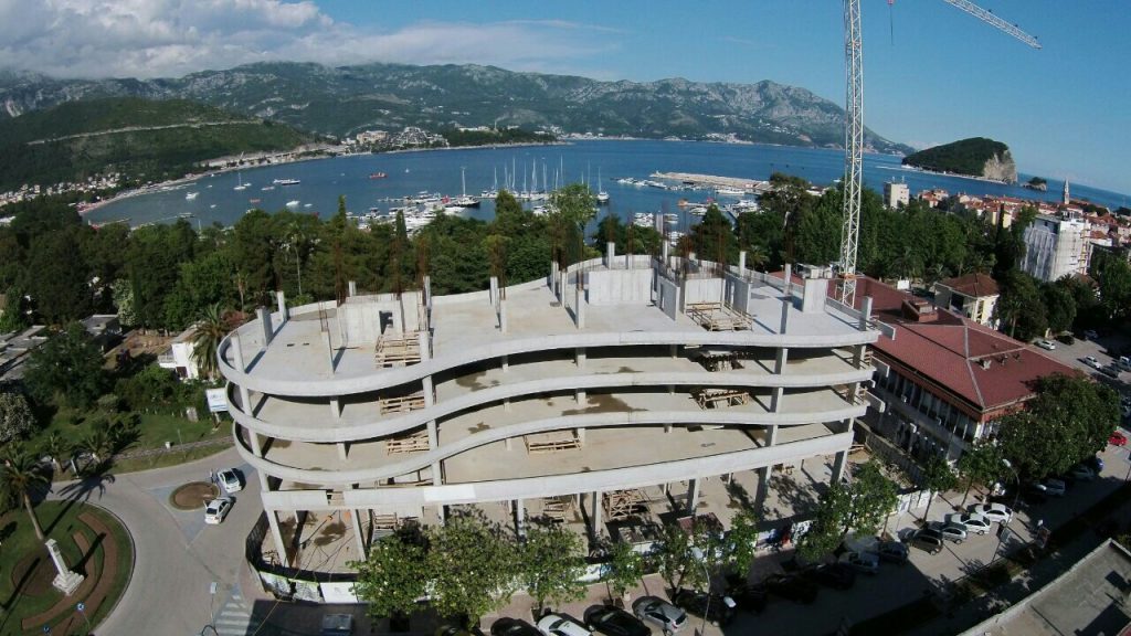 Im Bau befindliche Wohnanlage in Budva, Montenegro: Luftaufnahme des monolithischen Gebäuderohbaus am Meer und am Yachthafen.