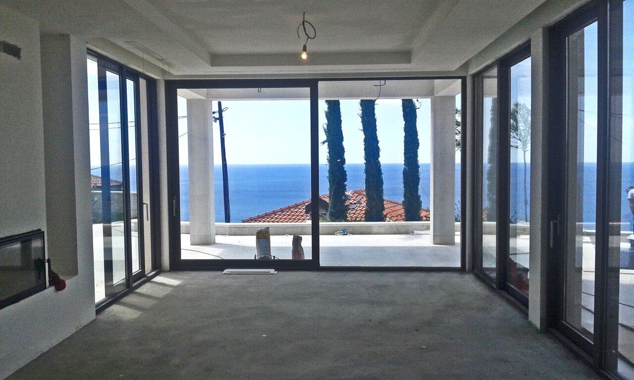 Wohnzimmer mit Panoramafenstern und Meerblick in einer im Bau befindlichen Villa in Reževići, Montenegro.