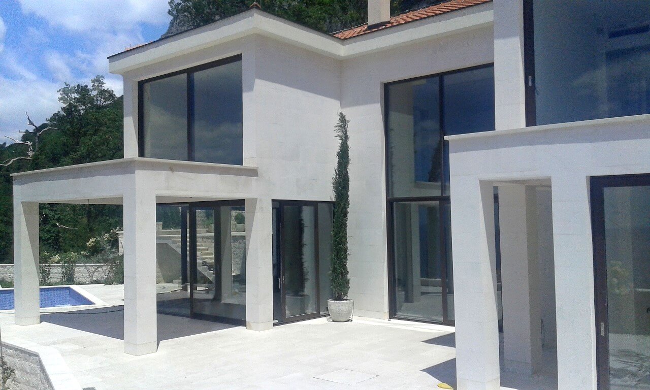 Moderne Villa mit Panoramafenstern, Terrasse und Pool in Reževići, Montenegro: Blick auf die Hausfassade.