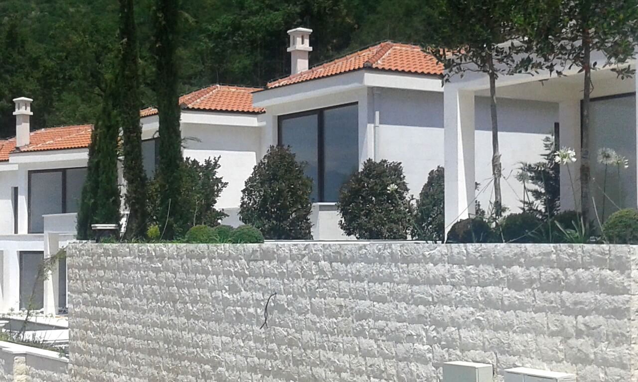 Moderne Villen mit Ziegeldach und Steinzaun in Reževići, Montenegro, Blick auf die Fassade und die Landschaft.