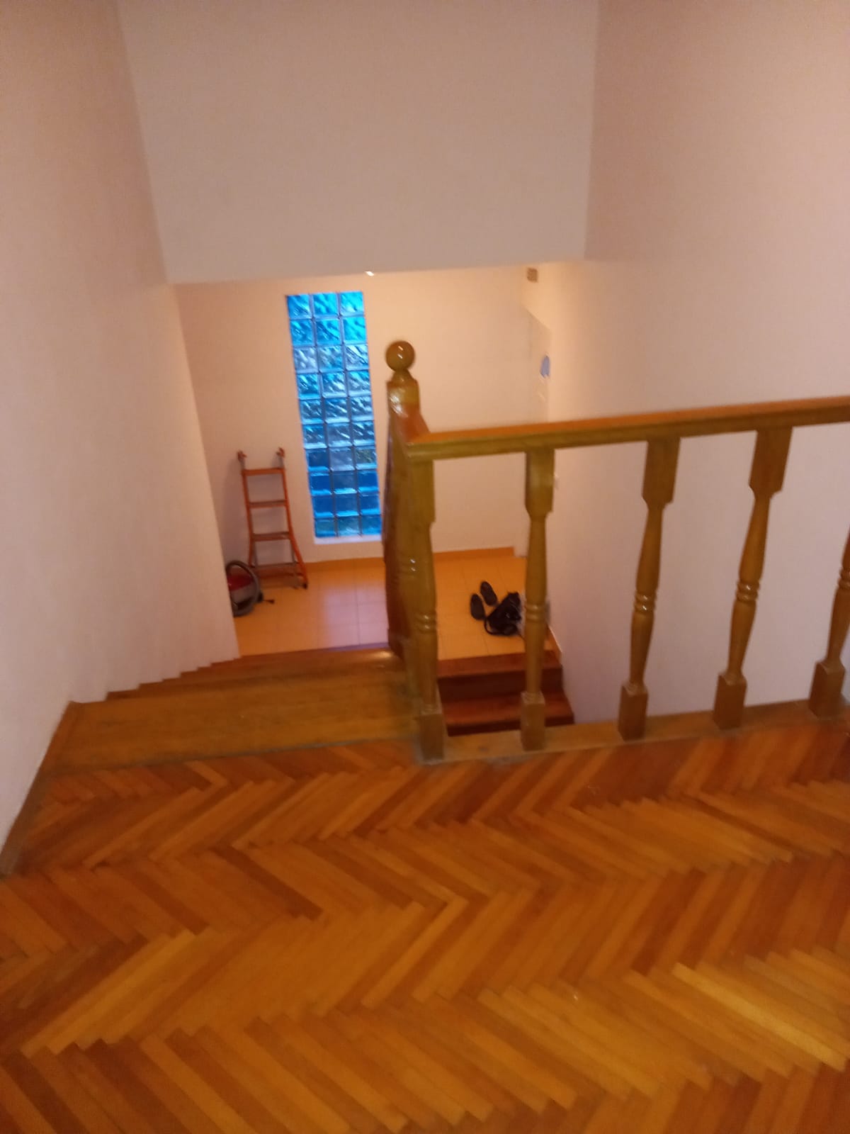 Holztreppe mit Balustern und Parkett im Hotel in Budva, Montenegro, mit dekorativem Fenster aus Glasbausteinen.