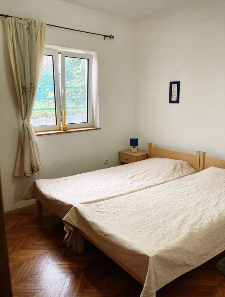Schlafzimmer in einem Hotel in Budva, Montenegro: zwei Einzelbetten, Holzboden, helle Wände und ein Fenster mit Blick auf die Straße.