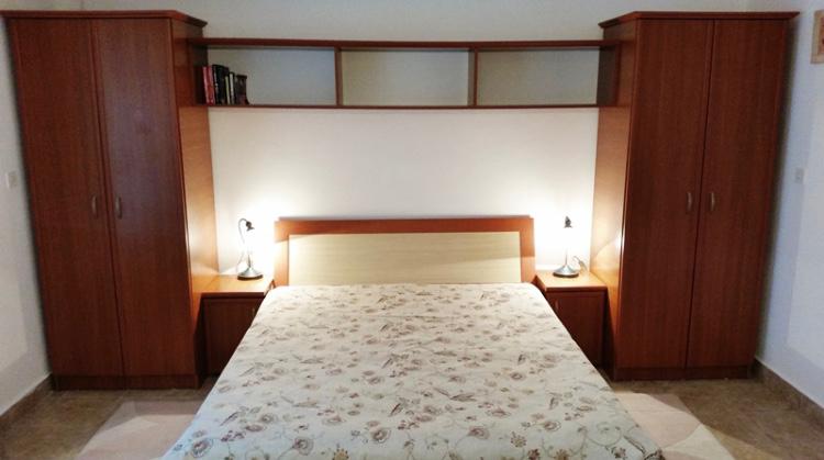 Schlafzimmer mit Doppelbett und Einbauschränken im Hotel, Budva, Montenegro. Gemütliches Interieur mit Nachttischlampen.