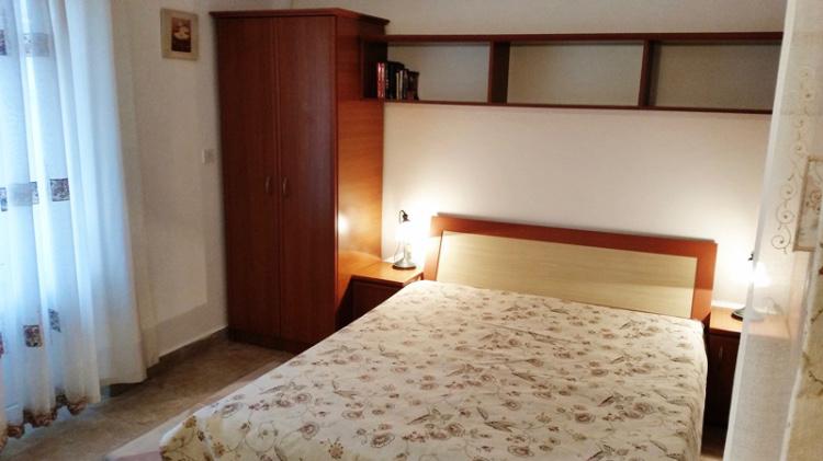 Gemütliches Schlafzimmer in einem Hotel in Budva, Montenegro: Doppelbett, Holzschrank, Nachttische und Regale.