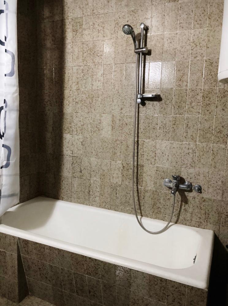 Badezimmer mit weißer Badewanne und beiger Fliesenverkleidung in einem Hotel in Budva, Montenegro.
