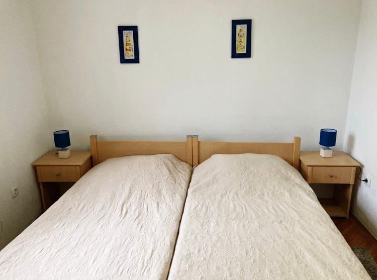 Schlafzimmer in einem Hotel in Budva, Montenegro: Doppelbett mit Holz-Kopfteil, Nachttische und blaue Lampen.
