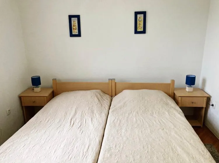 Schlafzimmer in einem Hotel in Budva, Montenegro: Doppelbett mit Holz-Kopfteil, Nachttische und blaue Lampen.