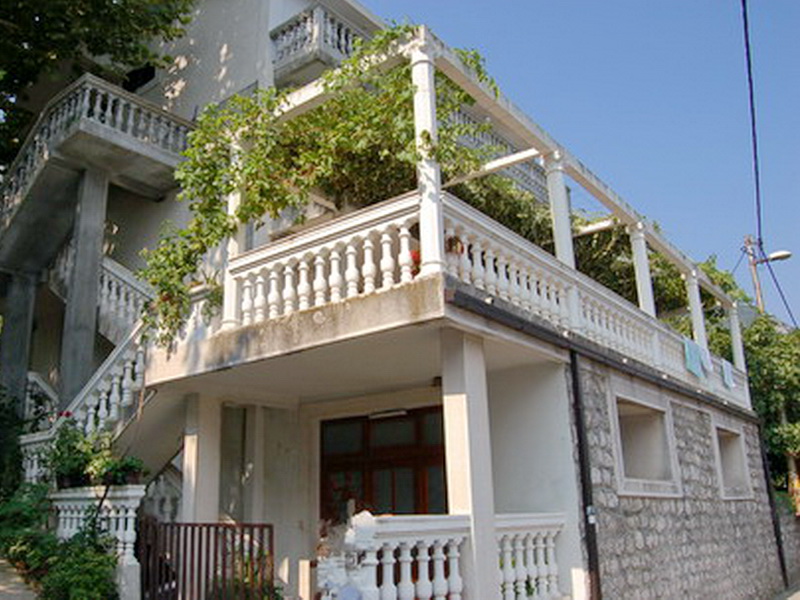 Zweistöckige Villa in Prčanj, Montenegro, mit Steinverkleidung, großzügiger Terrasse und von Grün umrankter Pergola.
