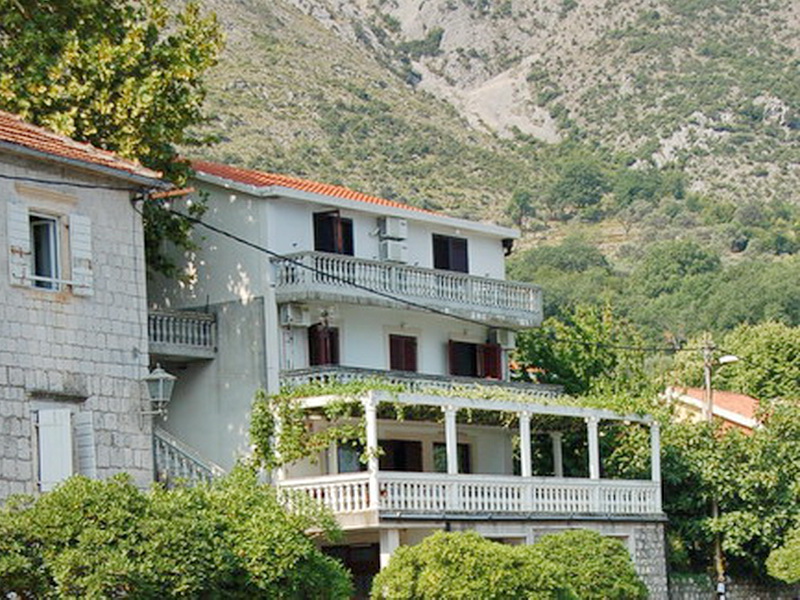 Dreistöckige Villa in Prčanj, Montenegro, mit Terrassen, Steinverkleidung und Bergblick inmitten von Grün.