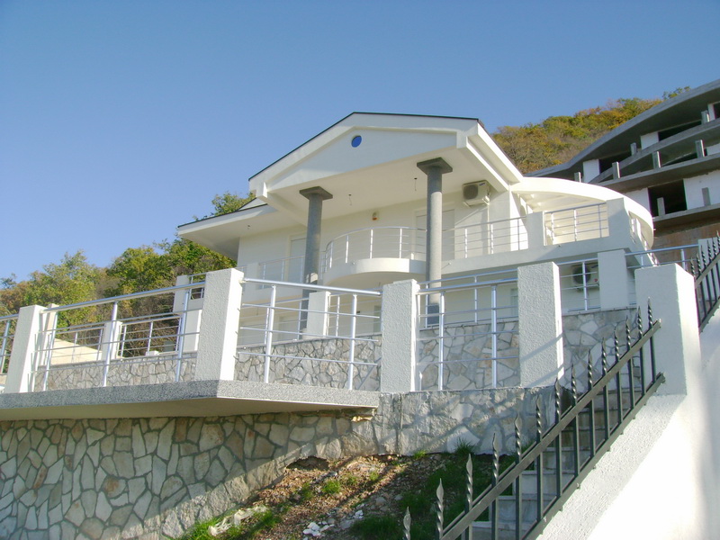 Белая вилла с террасой и каменной отделкой фасада в городе Бар, Черногория: вид на дом с лестницей и колоннами.