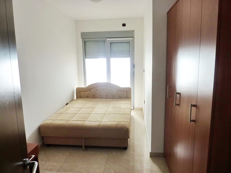 Schlafzimmer in einer Wohnung in Rafailovici, Montenegro: Doppelbett, Einbauschrank und Zugang zum Balkon mit Rollläden.