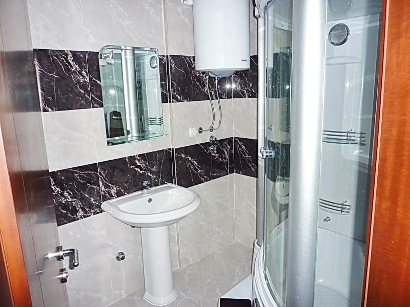 Badezimmer in der Wohnung, Rafailovići, Montenegro: Duschkabine, Waschbecken und Boiler, gefliestes Interieur.