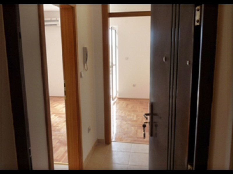 Hall d’entrée avec porte métallique et parquet dans un appartement à vendre à Igalo, Monténégro.