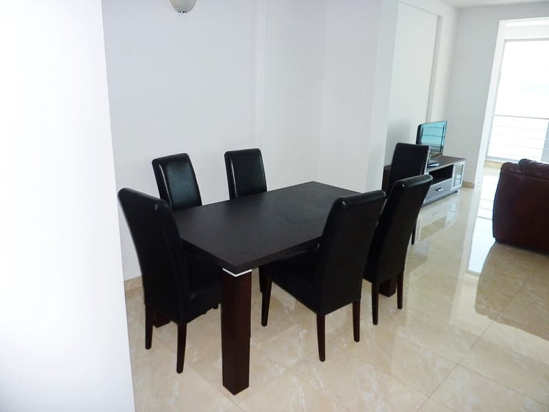 Essbereich mit dunklem Tisch und Stühlen in einer modernen Wohnung in Rafailovići, Montenegro, helles Interieur.