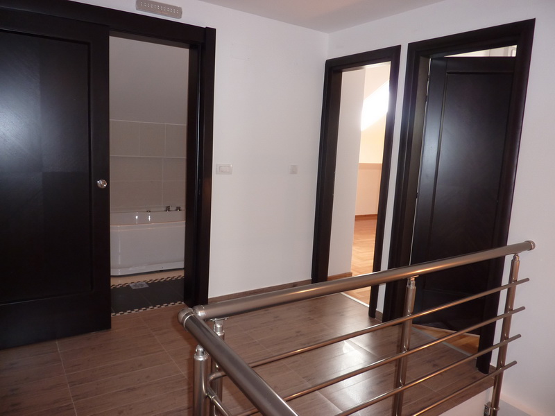 Innenraum einer Wohnung in Budva, Montenegro: heller Flur mit dunklen Innentüren und Blick auf das Badezimmer.