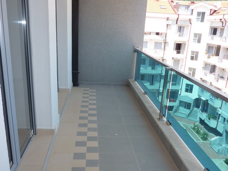 Geräumiger Balkon mit Panoramaverglasung in der Wohnung, Budva, Montenegro: Fliesenboden und Blick auf die Wohnanlage.