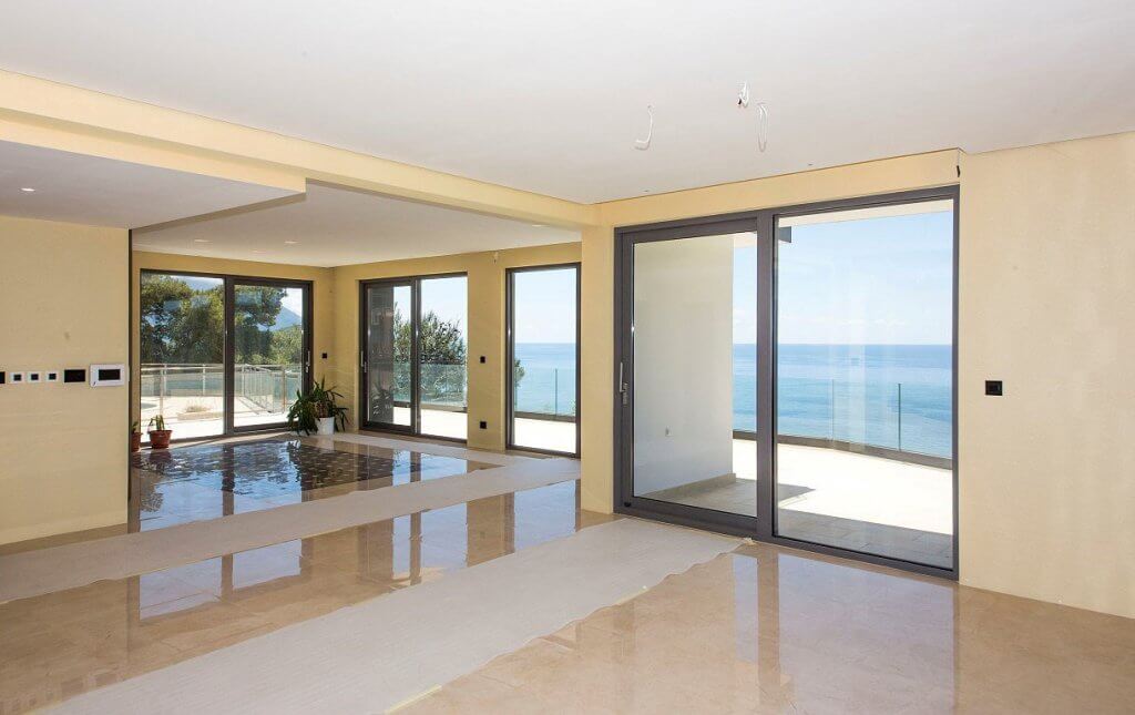 Geräumiges Wohnzimmer in einer Villa in Budva, Montenegro, mit Panoramafenstern, Marmorboden und direktem Meerblick.