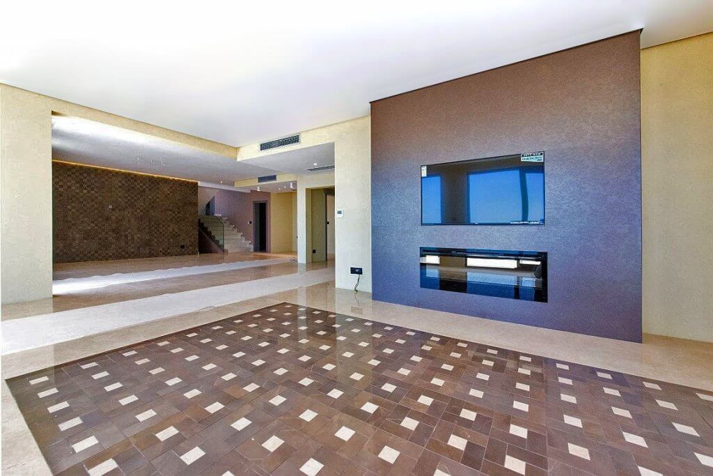 Geräumiges Wohnzimmer der Villa in Budva, Montenegro: modernes Design, Marmorboden, eingebauter Kamin und TV-Bereich.