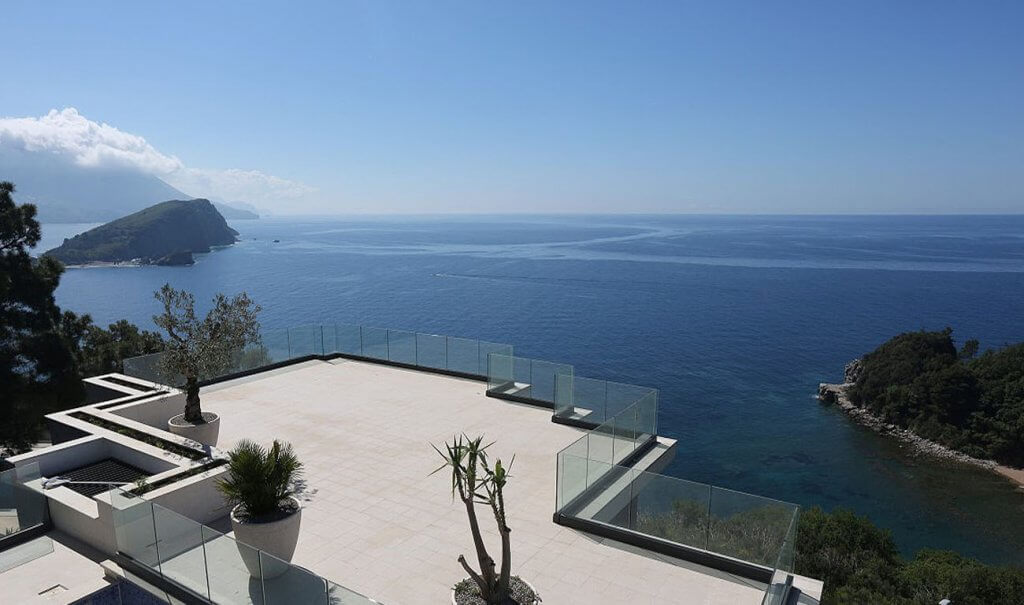Panorama-Terrasse der Villa in Budva, Montenegro, mit Glasgeländer und Blick auf die Adria und die Insel.