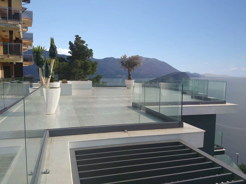 Geräumige Terrasse der Villa in Budva, Montenegro, mit Glasgeländer, Bodenfliesen und Panoramablick auf das Meer.