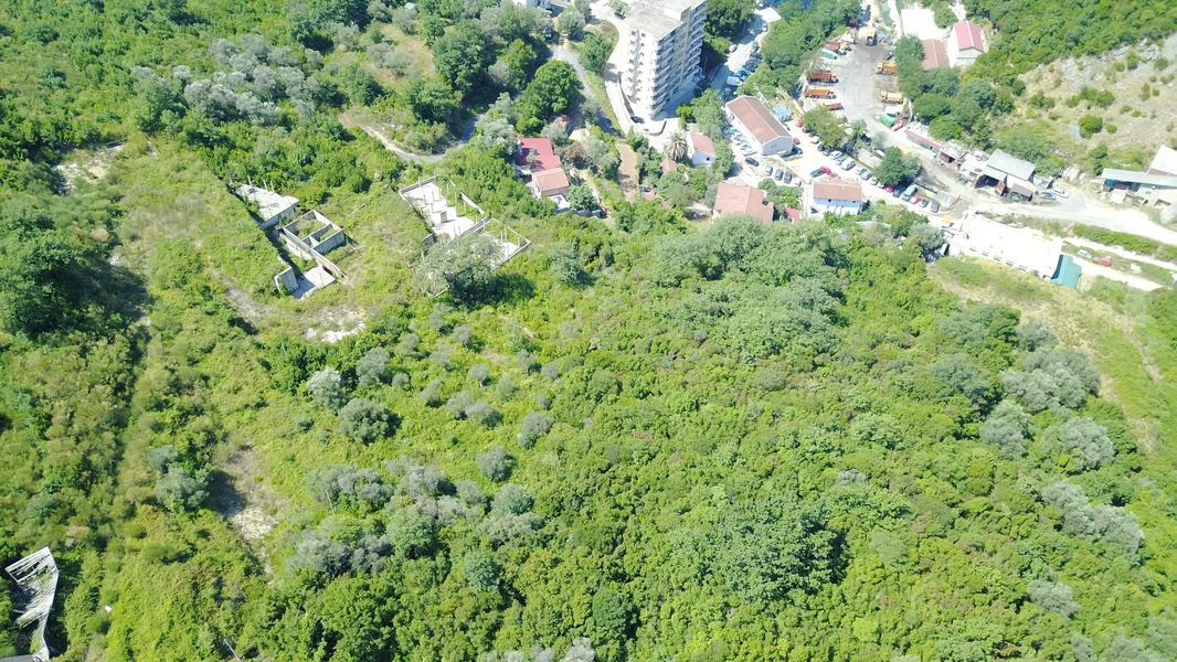 Baugrundstück in Bečići, Montenegro: Blick von oben auf das Gelände mit dichter Begrünung und Infrastruktur.