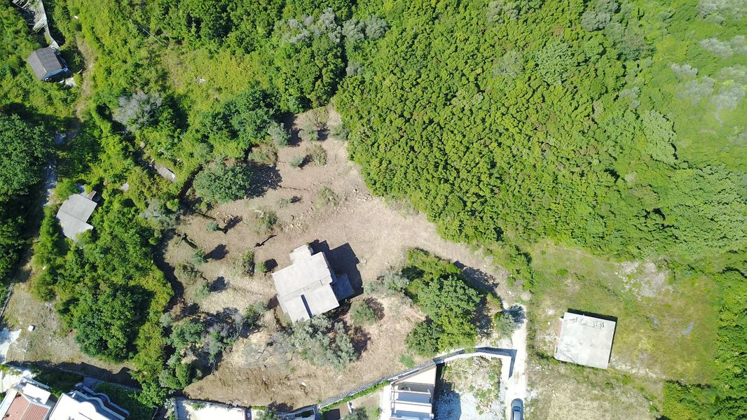 Baugrundstück in Bečići, Montenegro: Luftaufnahme des Geländes mit Haus und Grünanlagen.