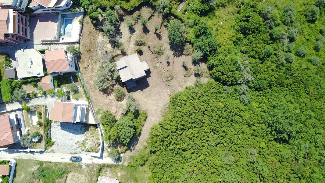 Baugrundstück in Bečići, Montenegro: Blick von oben auf das Grundstück mit Haus und Grünfläche.