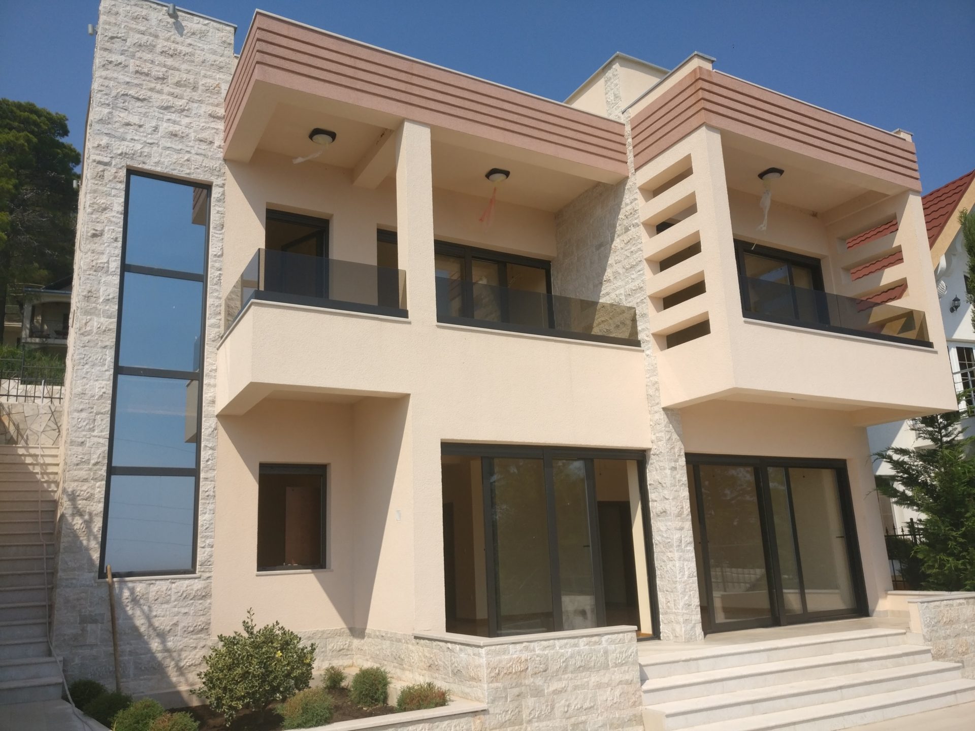 Modernes zweistöckiges Haus in Šušanj, Montenegro: Panoramafenster, Terrassen mit Glasgeländern und Steinverkleidung.