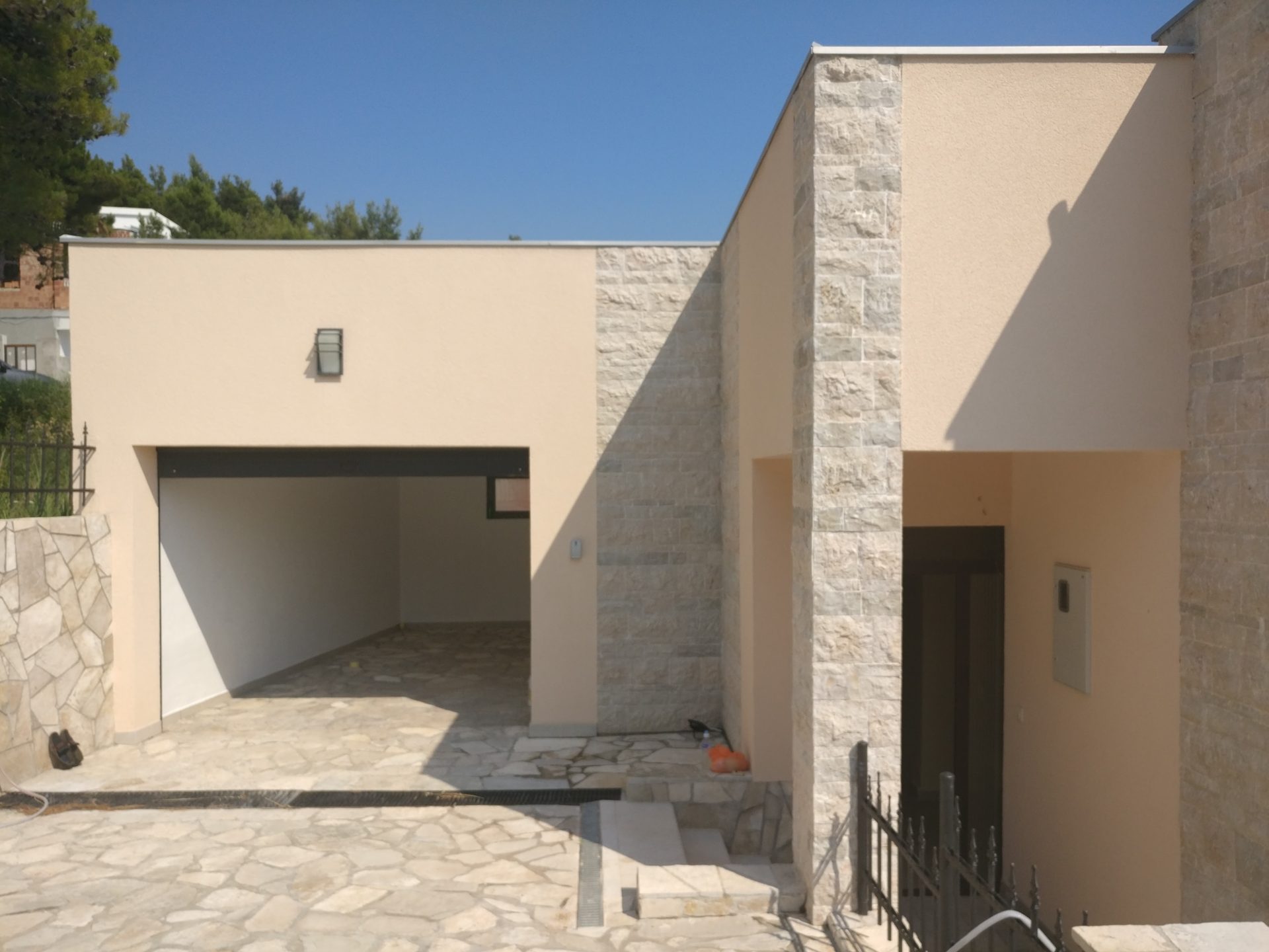 Modernes Haus in Šušanj, Montenegro: Fassade mit Steinverkleidung, Garage und Eingangsbereich, Außenansicht.