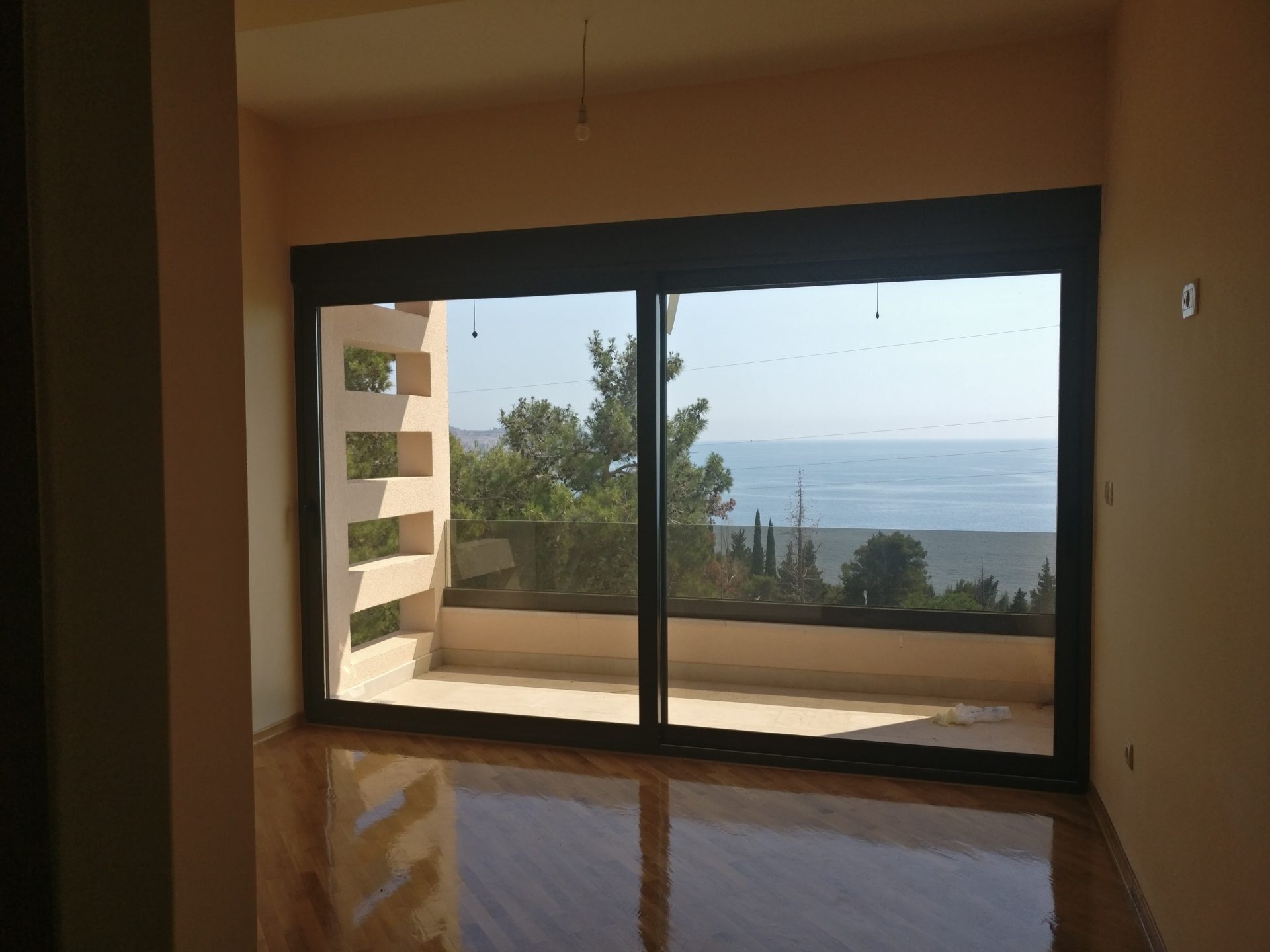 Wohnzimmer mit Panoramafenster und Meerblick im Haus, Šušanj, Montenegro: Parkettboden und Zugang zur Terrasse.