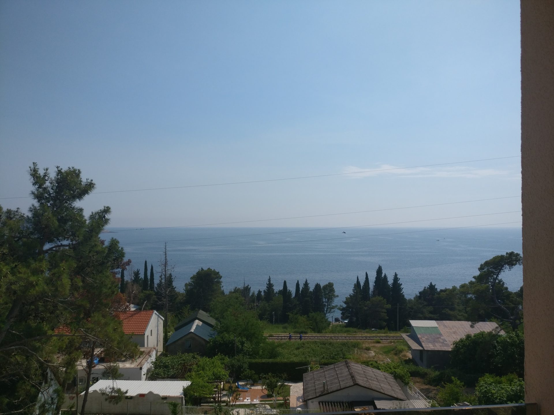 Blick auf die Adria vom Balkon eines Hauses in Šušanj, Montenegro: Panorama der Küste, Grün und private Bebauung.