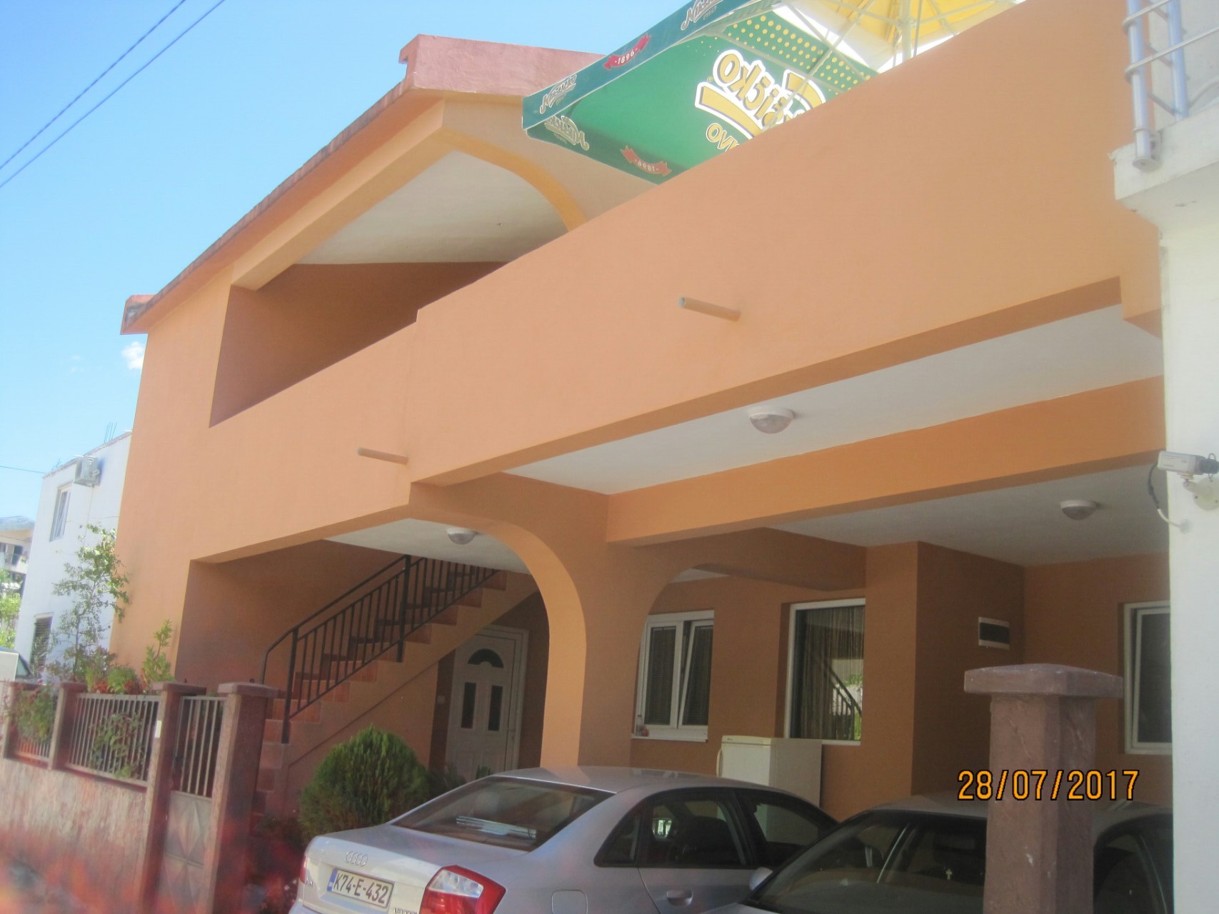 Zweistöckiges Haus mit Terrassen und Parkplatz in Šušanj, Montenegro: Gebäudefassade mit Außentreppe und Autos.