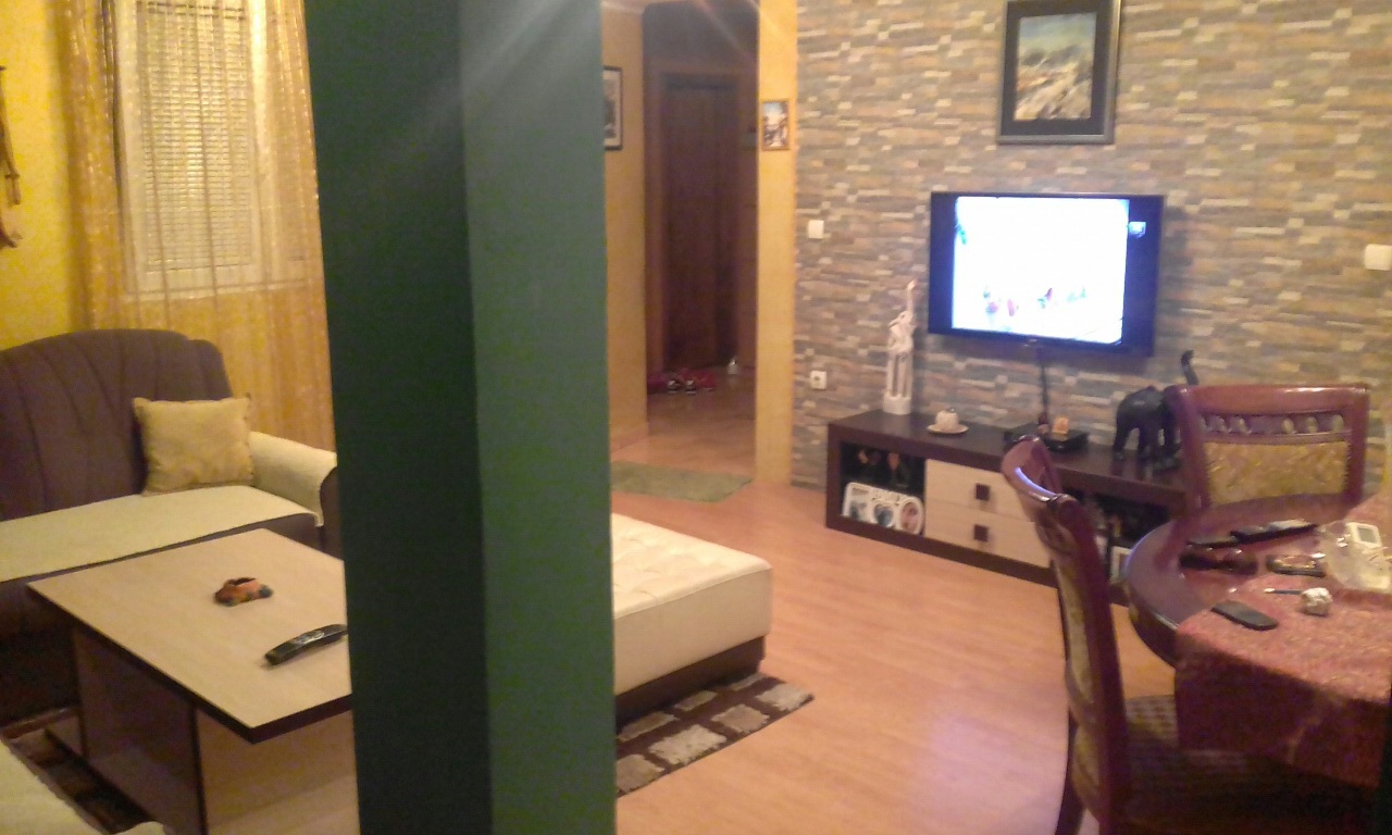 Innenraum des Wohnzimmers in einem Haus in Šušanj, Montenegro: ein weiches Sofa, ein Essbereich und eine Wand mit dekorativer Steinverkleidung.