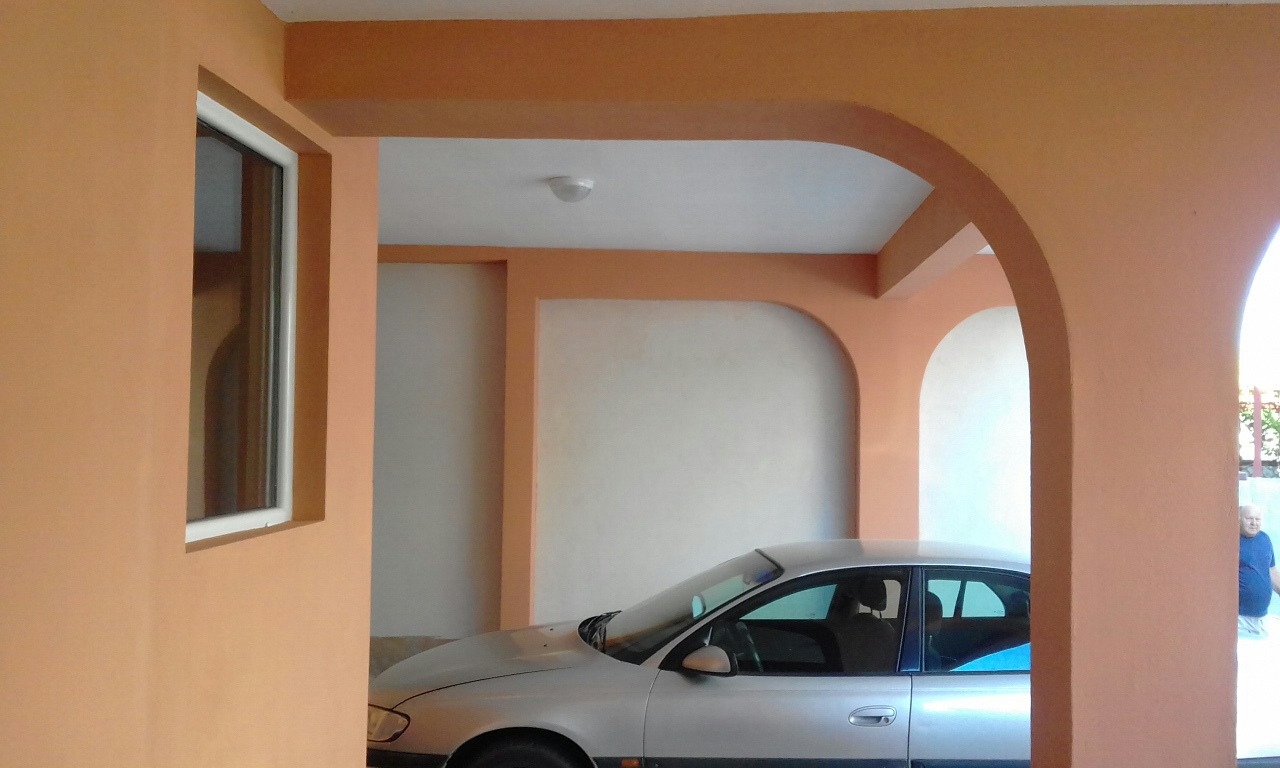 Überdachter Parkplatz mit Bogenöffnungen am Haus in Shushan, Montenegro: Blick auf den Carport und die Fassade des Gebäudes.