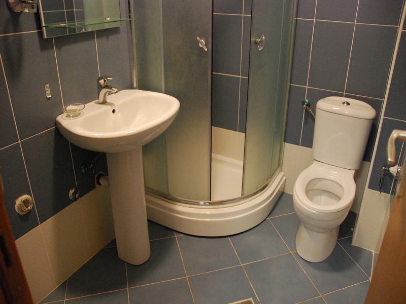 Ein kompaktes modernes Badezimmer mit Standwaschbecken, Duschkabine und Toilette.