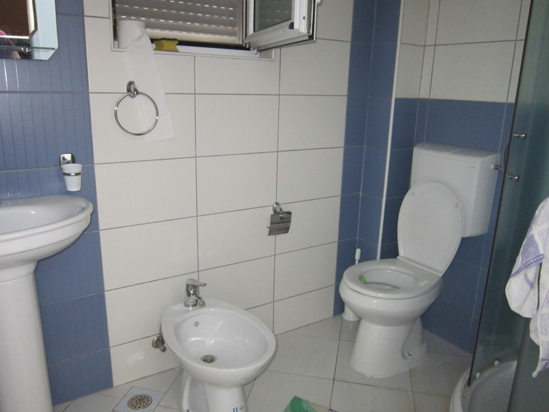 Badezimmer in einem Haus in Utjeha, Montenegro: weiße Sanitärkeramik, Bidet, Duschkabine und weiß-blaue Fliesen an den Wänden.