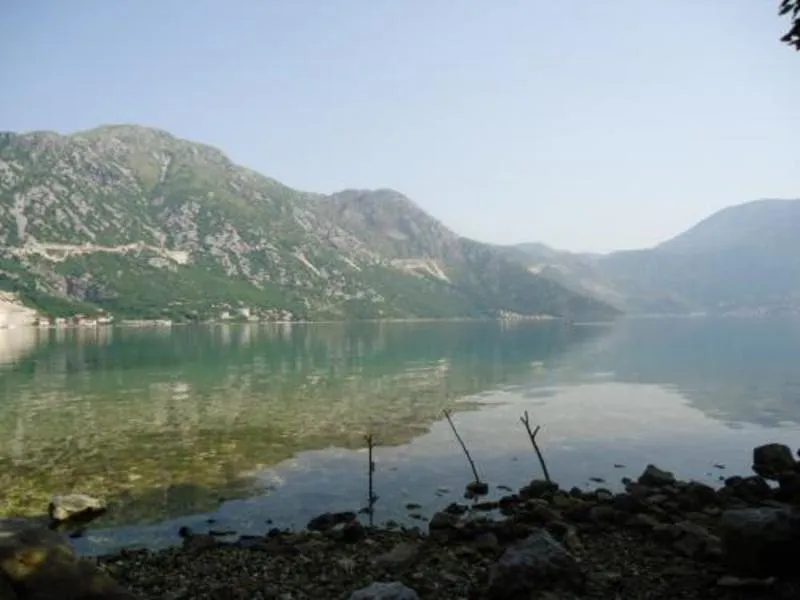 Široki pogled na mirno jezero okruženo planinama po vedrom danu.